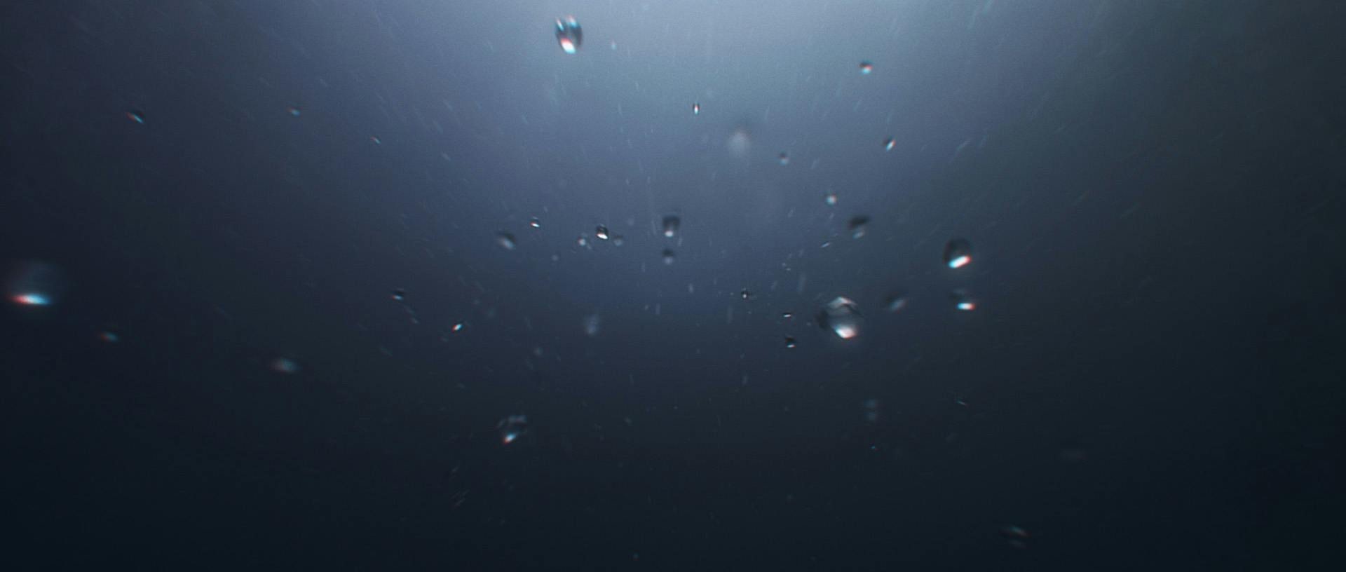 Bubbles underwater in a dark ocean.